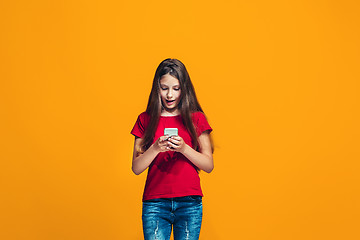 Image showing The happy teen girl standing and smiling against orange background.