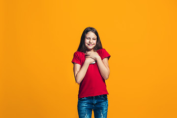 Image showing The happy teen girl standing and smiling against orange background.