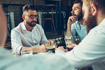 Image showing Young cheerful people smile and gesture while relaxing in pub.