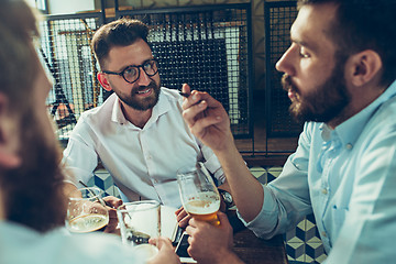 Image showing Young cheerful people smile and gesture while relaxing in pub.