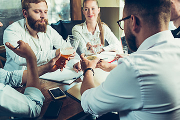 Image showing Young cheerful people smile and gesture while relaxing in pub.