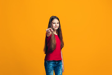 Image showing The happy teen girl pointing to you, half length closeup portrait on orange background.