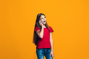 Image showing The happy teen girl standing and smiling against orange background.