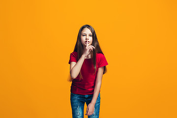 Image showing The young teen girl whispering a secret behind her hand over orange background