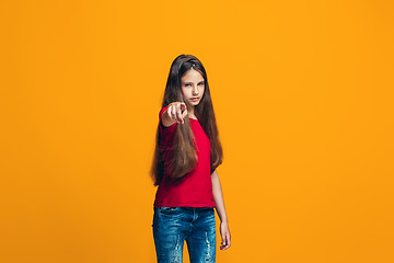Image showing The happy teen girl pointing to you, half length closeup portrait on orange background.