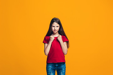 Image showing Portrait of angry teen girl on a orange studio background