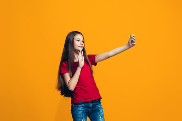 Image showing The happy teen girl standing and smiling against orange background.