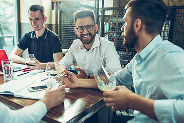 Image showing Young cheerful people smile and gesture while relaxing in pub.