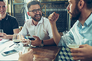 Image showing Young cheerful people smile and gesture while relaxing in pub.