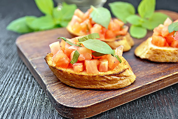 Image showing Bruschetta with tomato and basil on wooden board