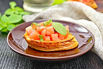 Image showing Bruschetta with tomato and basil in brown plate on board