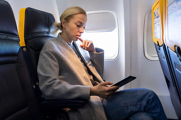 Image showing Woman reading on digital e-reader while traveling by airplane.