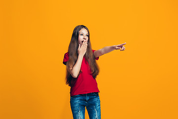 Image showing The happy teen girl pointing to you, half length closeup portrait on orange background.