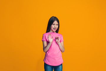 Image showing Doubtful pensive teen girl rejecting something against orange background