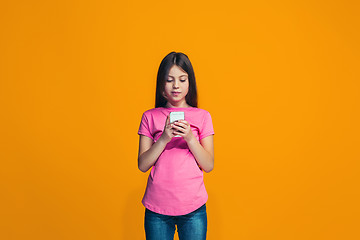 Image showing The happy teen girl standing and smiling against orange background.