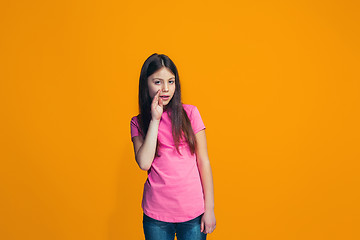 Image showing The young teen girl whispering a secret behind her hand over orange background