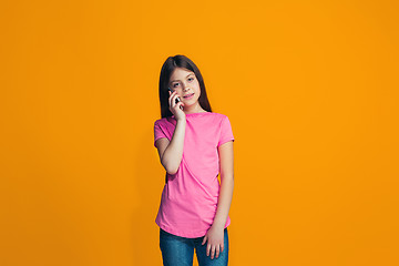 Image showing The happy teen girl standing and smiling against orange background.