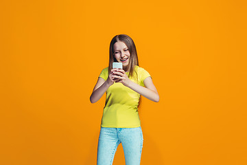 Image showing The happy teen girl standing and smiling against orange background.