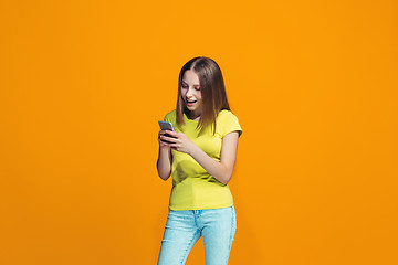 Image showing The happy teen girl standing and smiling against orange background.