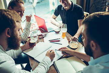 Image showing Young cheerful people smile and gesture while relaxing in pub.