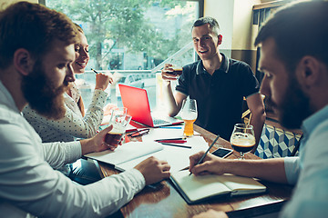 Image showing Young cheerful people smile and gesture while relaxing in pub.