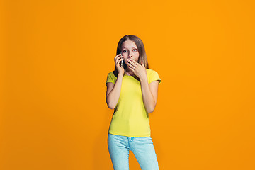 Image showing The happy teen girl standing and smiling against orange background.