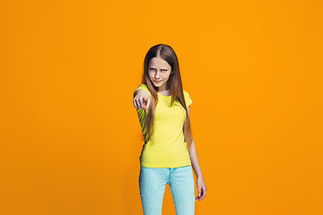 Image showing The happy teen girl pointing to you, half length closeup portrait on orange background.