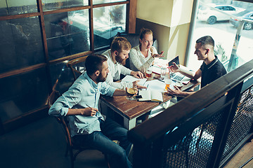 Image showing Young cheerful people smile and gesture while relaxing in pub.