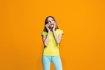 Image showing The happy teen girl standing and smiling against orange background.