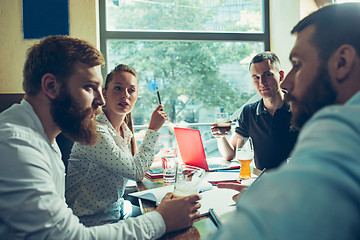 Image showing Young cheerful people smile and gesture while relaxing in pub.