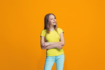 Image showing The happy teen girl standing and smiling against orange background.