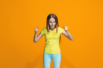 Image showing Portrait of angry teen girl on a orange studio background