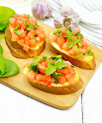 Image showing Bruschetta with tomato and spinach on white wooden board