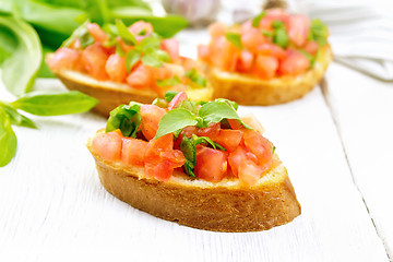 Image showing Bruschetta with tomato and spinach on light wooden board