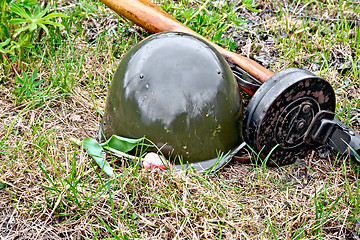 Image showing Helmet and submachine gun with tulip on grass