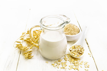 Image showing Milk oatmeal in jug on light wooden board