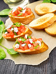 Image showing Bruschetta with tomato and cheese on wooden board