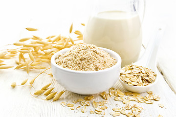 Image showing Flour oat in bowl with milk on light wooden board