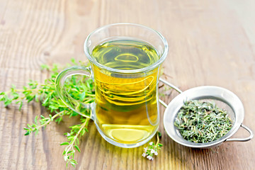 Image showing Tea of thyme in mug with strainer on old board