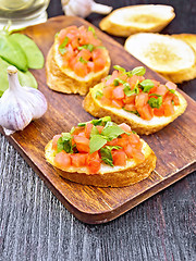 Image showing Bruschetta with tomato and spinach on dark wooden board