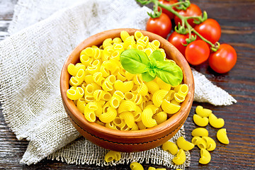 Image showing Elbow macaroni in bowl with tomatoes on dark board