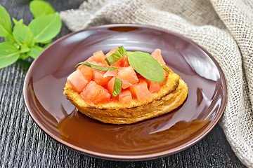 Image showing Bruschetta with tomato and basil in brown plate on dark board