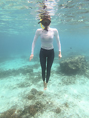 Image showing Woman with mask snorkeling in blue sea.