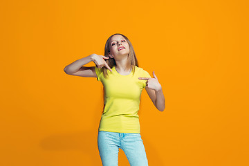 Image showing The happy teen girl standing and smiling against orange background.