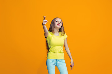 Image showing The happy teen girl pointing to you, half length closeup portrait on orange background.