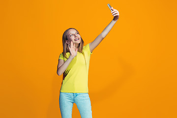 Image showing The happy teen girl standing and smiling against orange background.