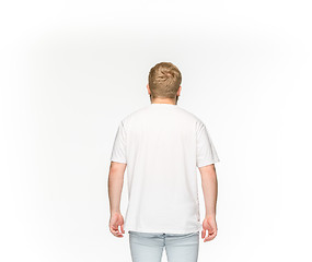 Image showing Closeup of young man\'s body in empty white t-shirt isolated on white background. Mock up for disign concept