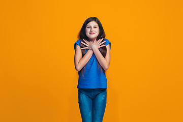 Image showing The happy teen girl standing and smiling against orange background.