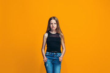 Image showing Portrait of angry teen girl on a orange studio background