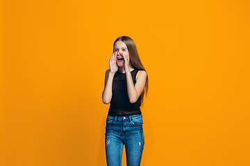 Image showing Isolated on yellow young casual teen girl shouting at studio